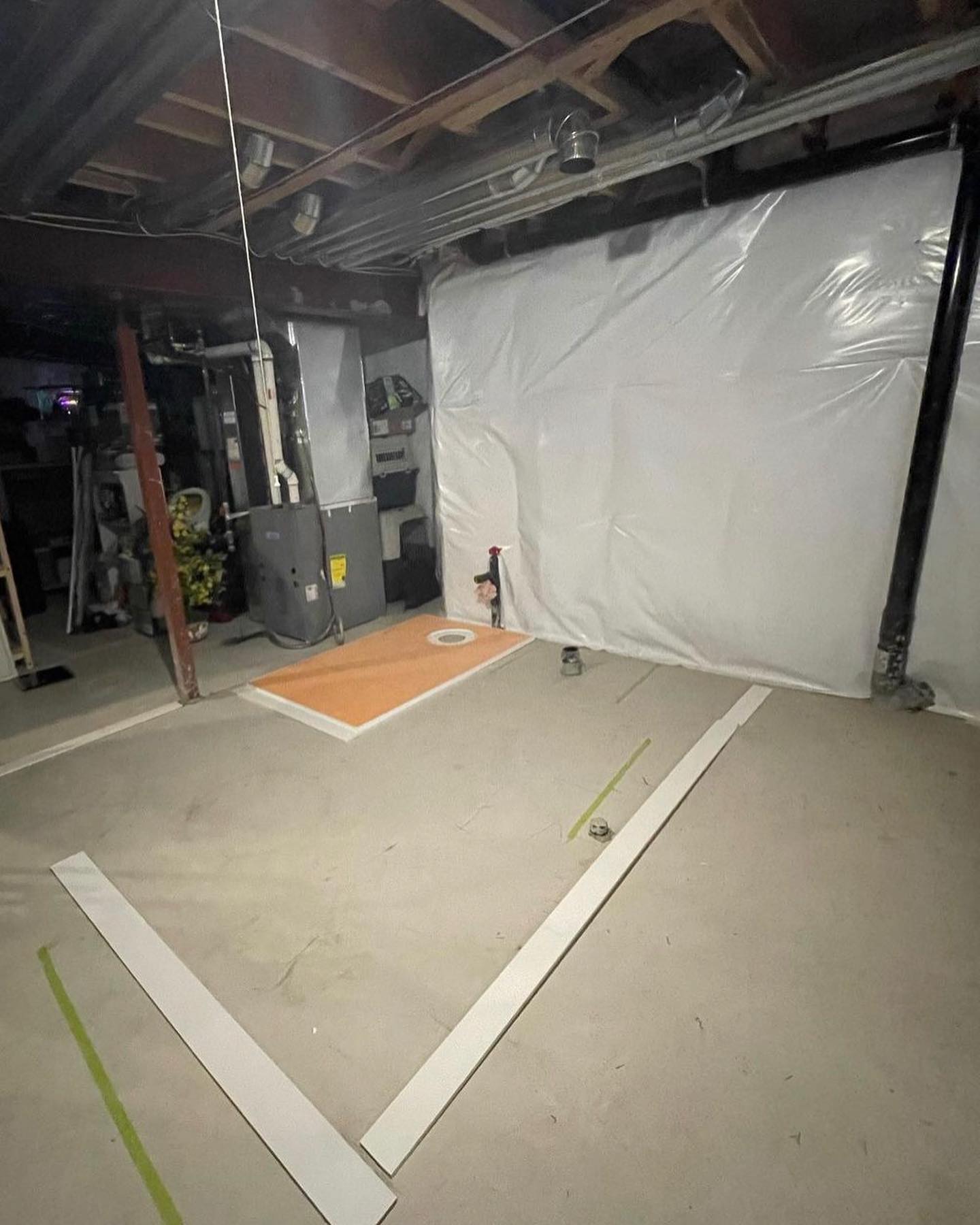 Unfinished basement space before the new bathroom build with concrete floor, support column, and temporary wall covering