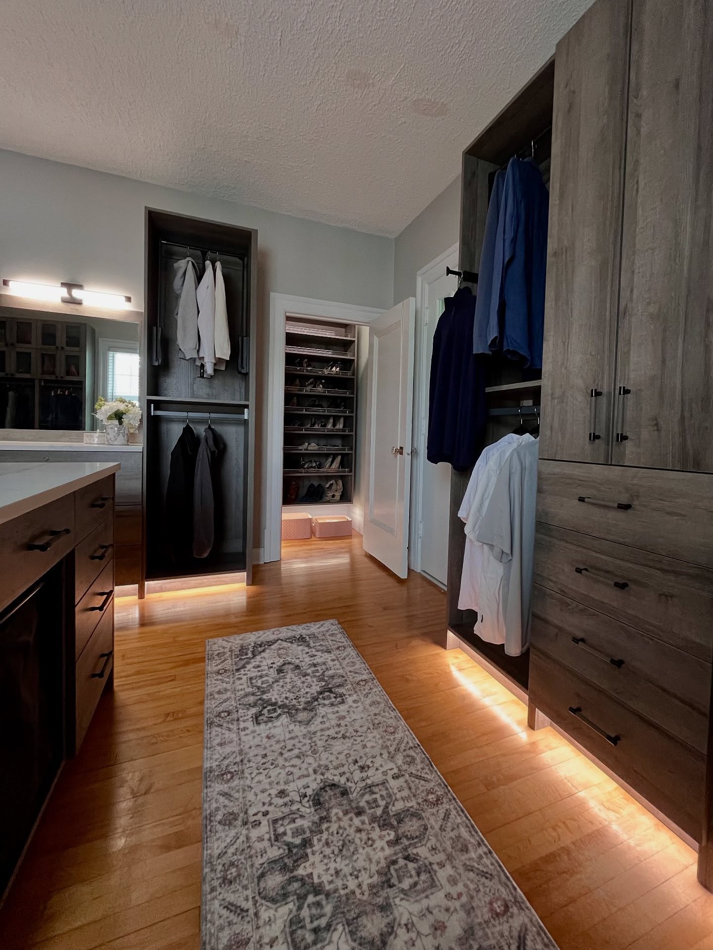 Converted Winnipeg wardrobe room with tall wood-tone cabinets, open hanging, and warm accent lighting