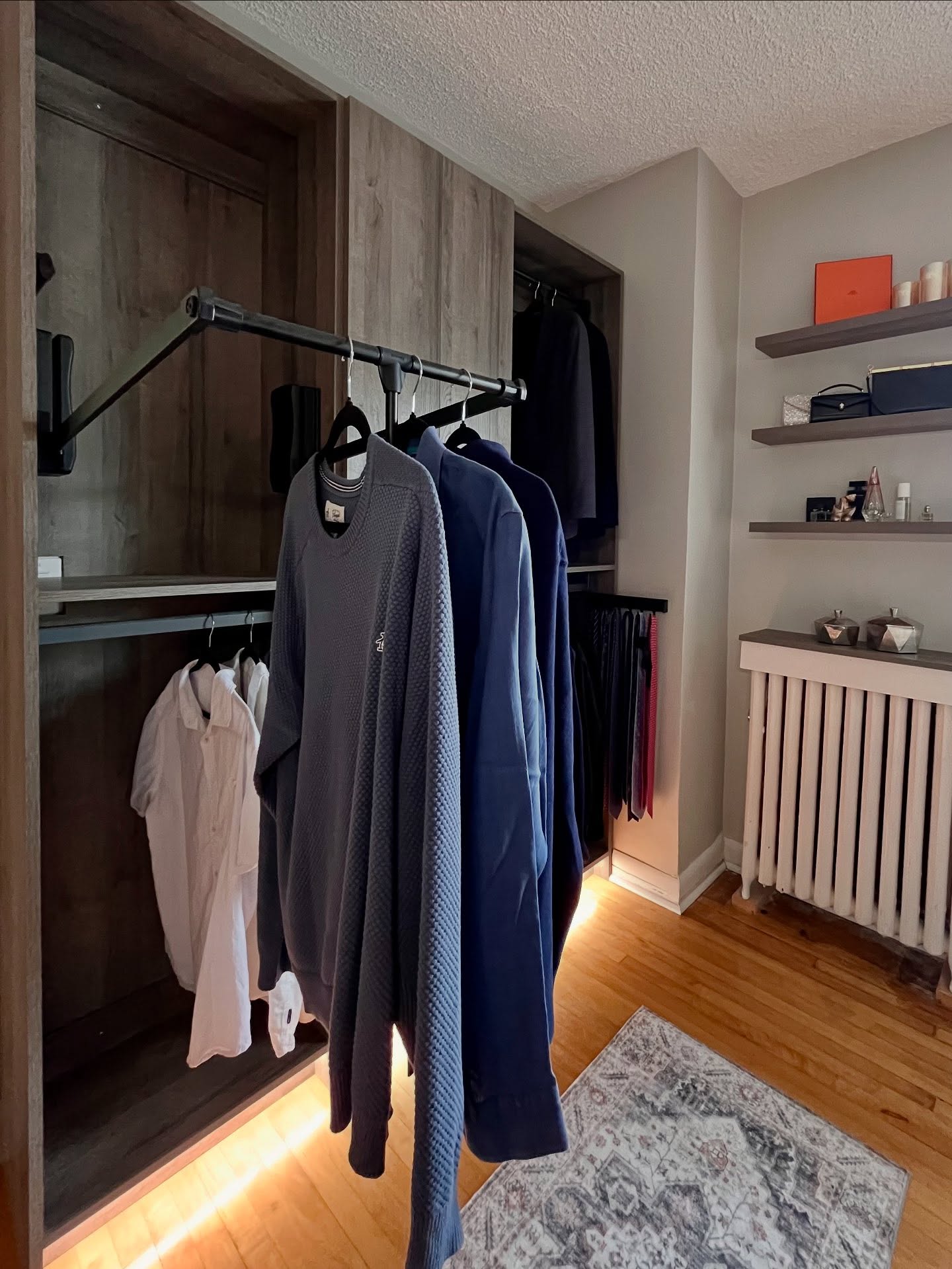 Wardrobe room storage wall with ordered hanging and soft wood finishes