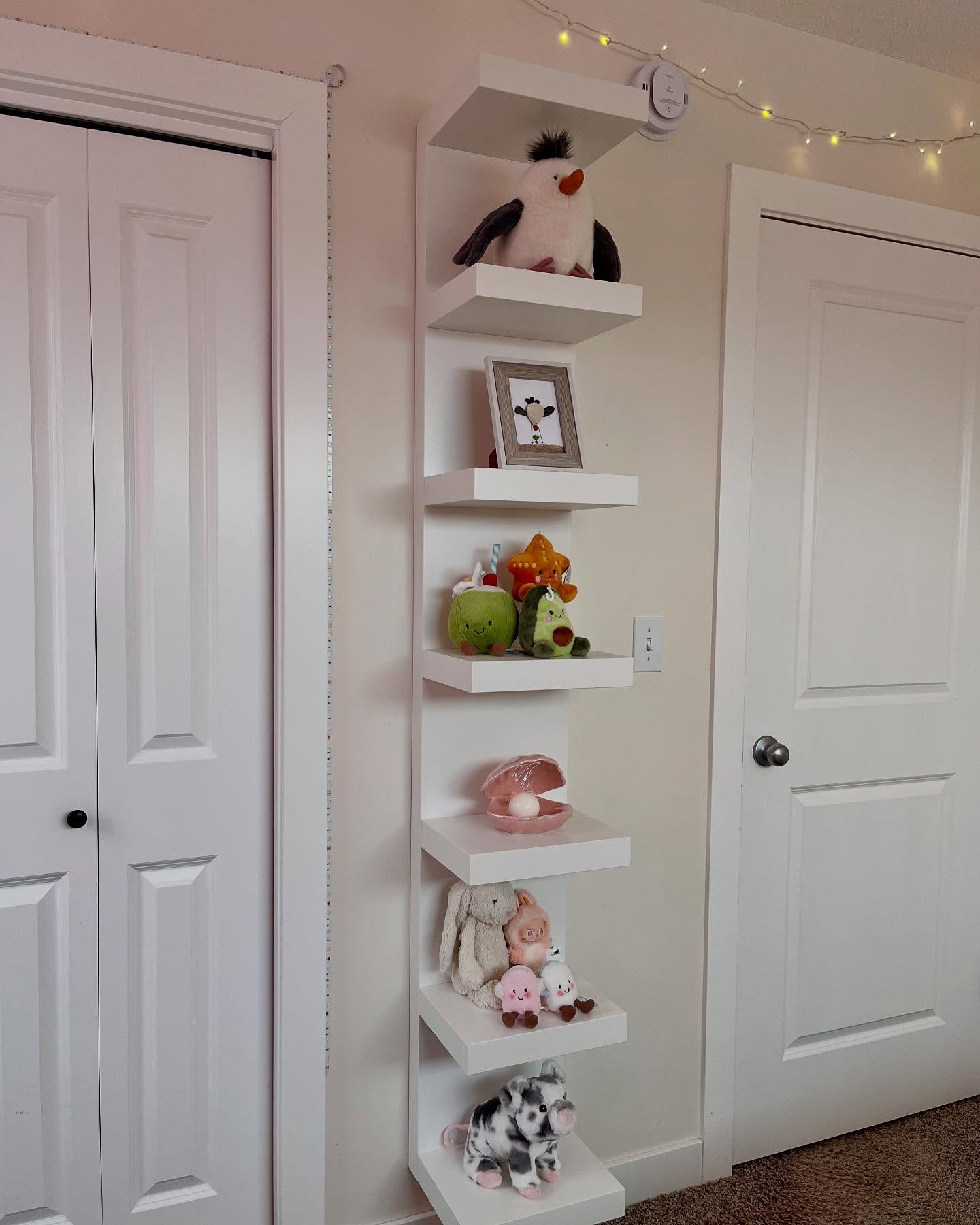 Open shelving styled with plush toys and decor in a girls bedroom