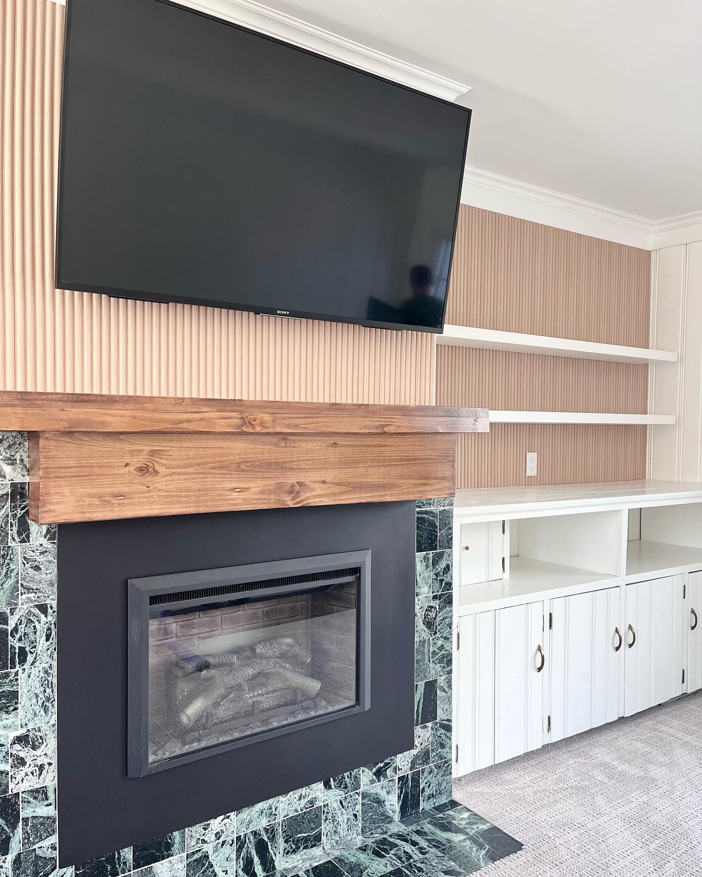 Winnipeg living room with a custom mantle, fireplace, mounted television, and fresh flooring