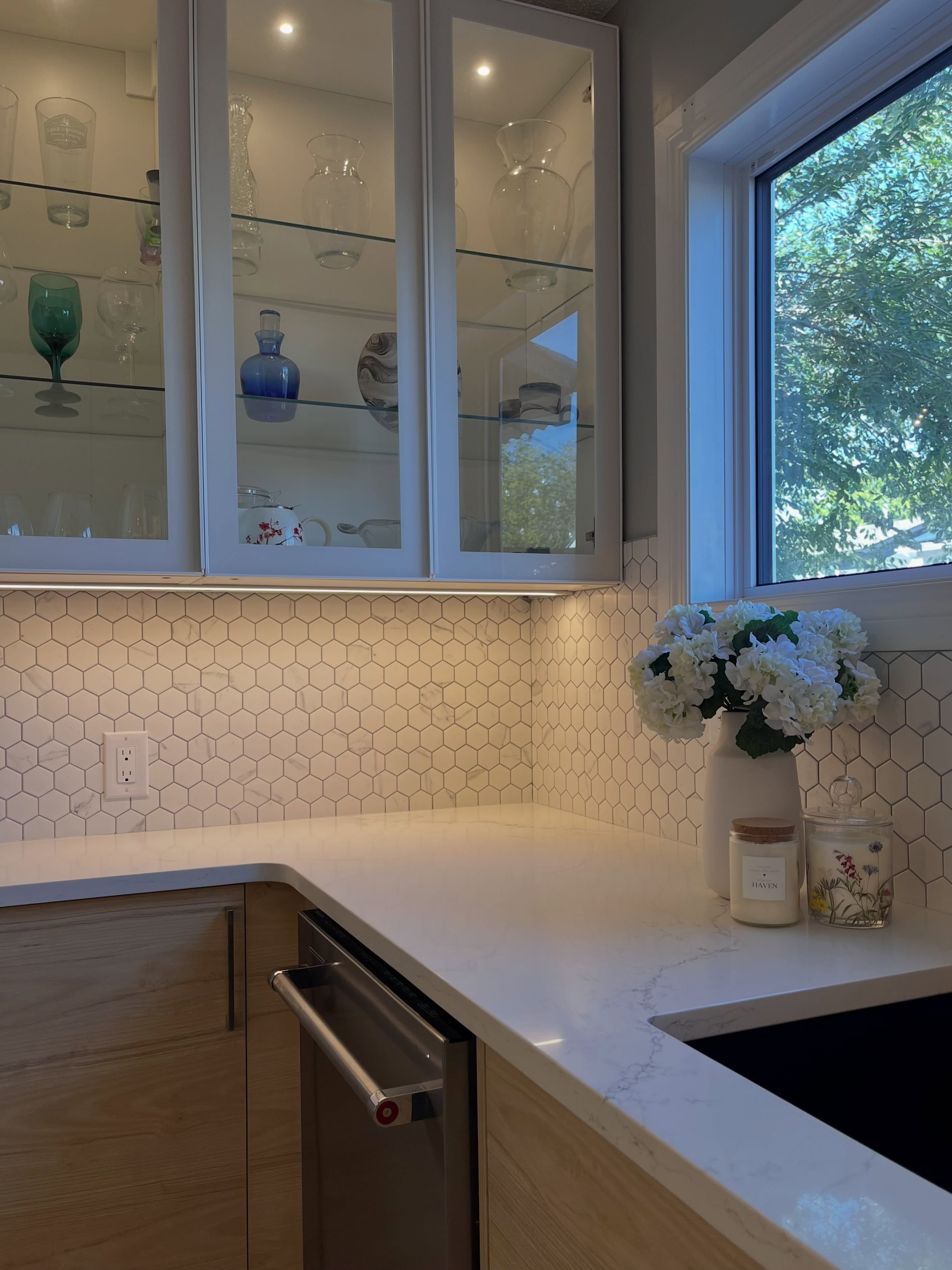 Finished Winnipeg kitchen sink and window wall with quartz counters and mixed white and wood cabinetry