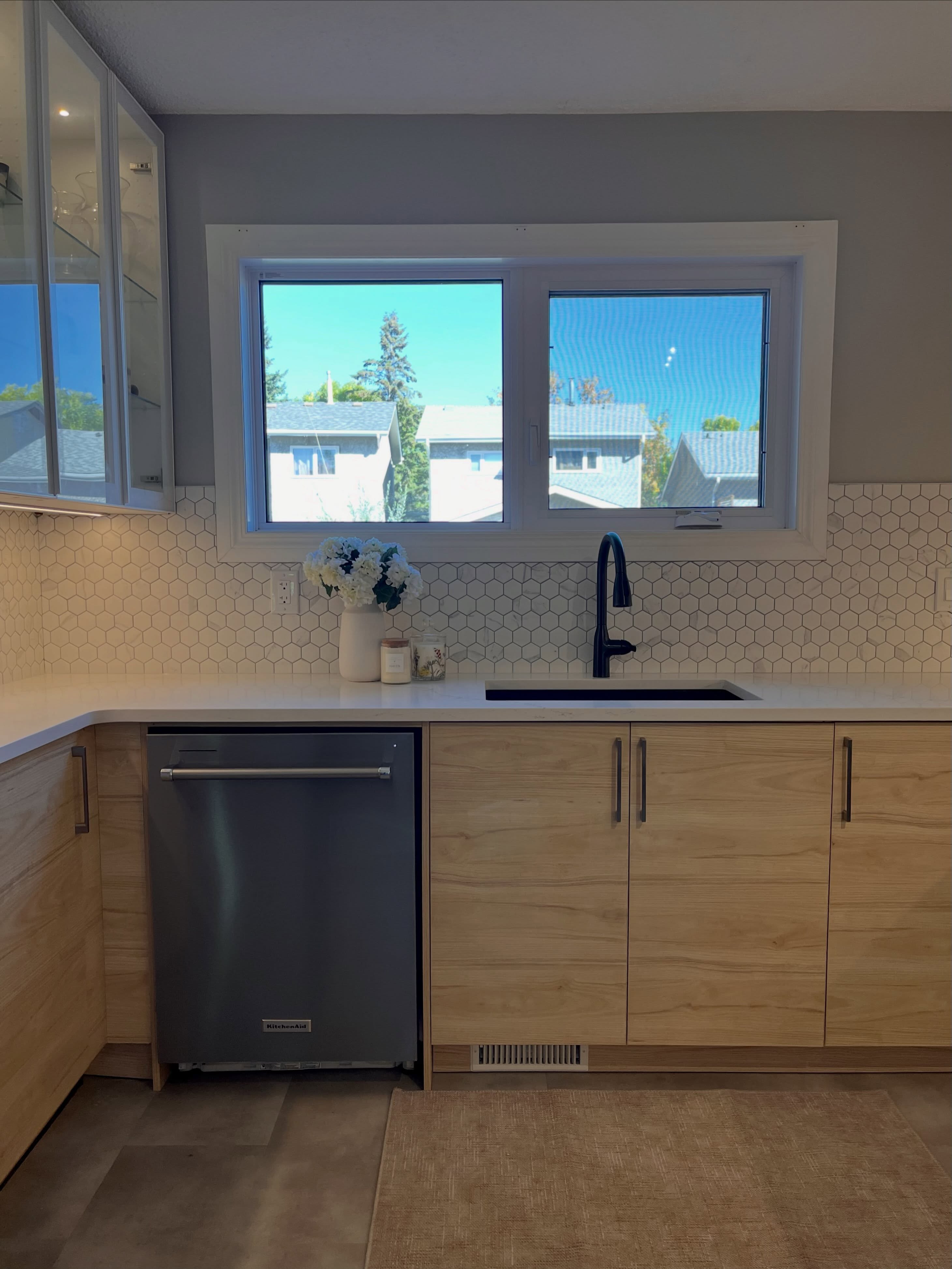 Finished Winnipeg kitchen dishwasher and sink run with quartz counters and hexagon tile